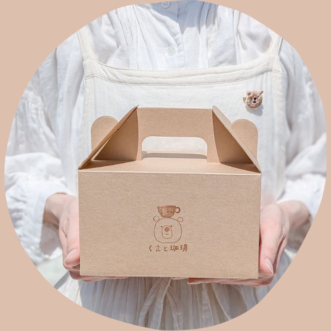 頭の上にコーヒーカップをのせたくまのスタンプがおされたケーキ箱